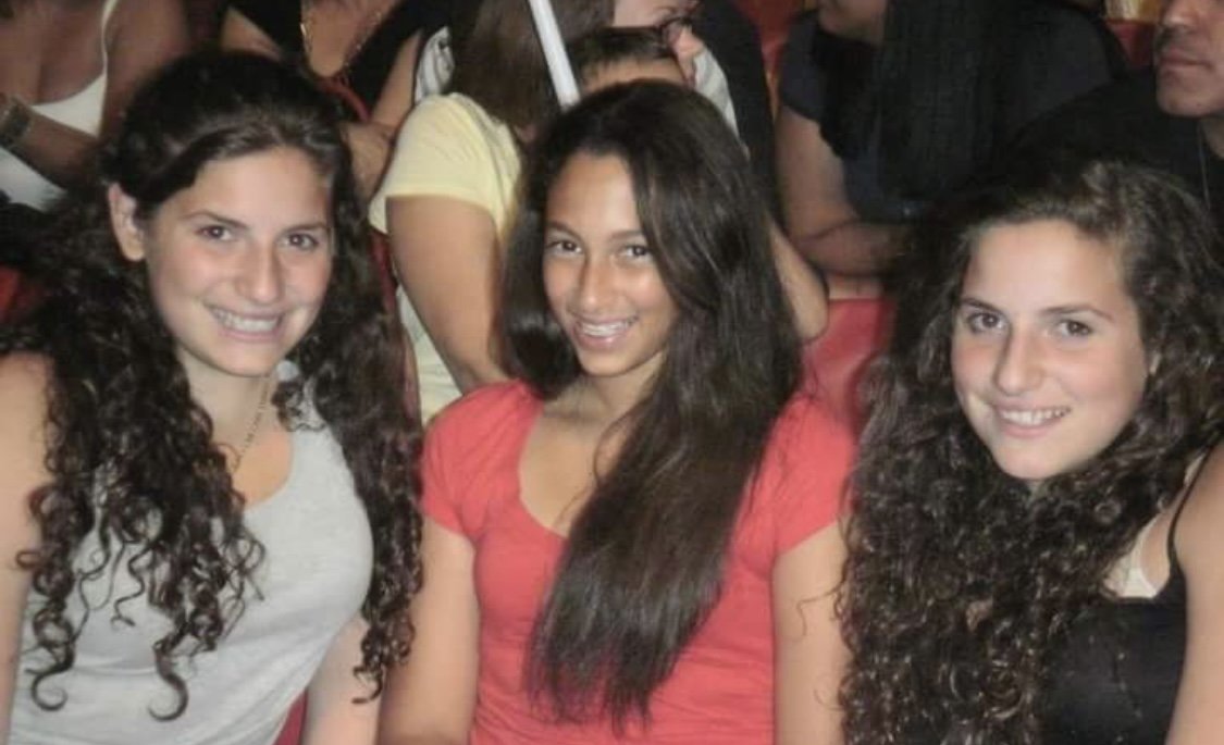 Three friends smiling together at an event