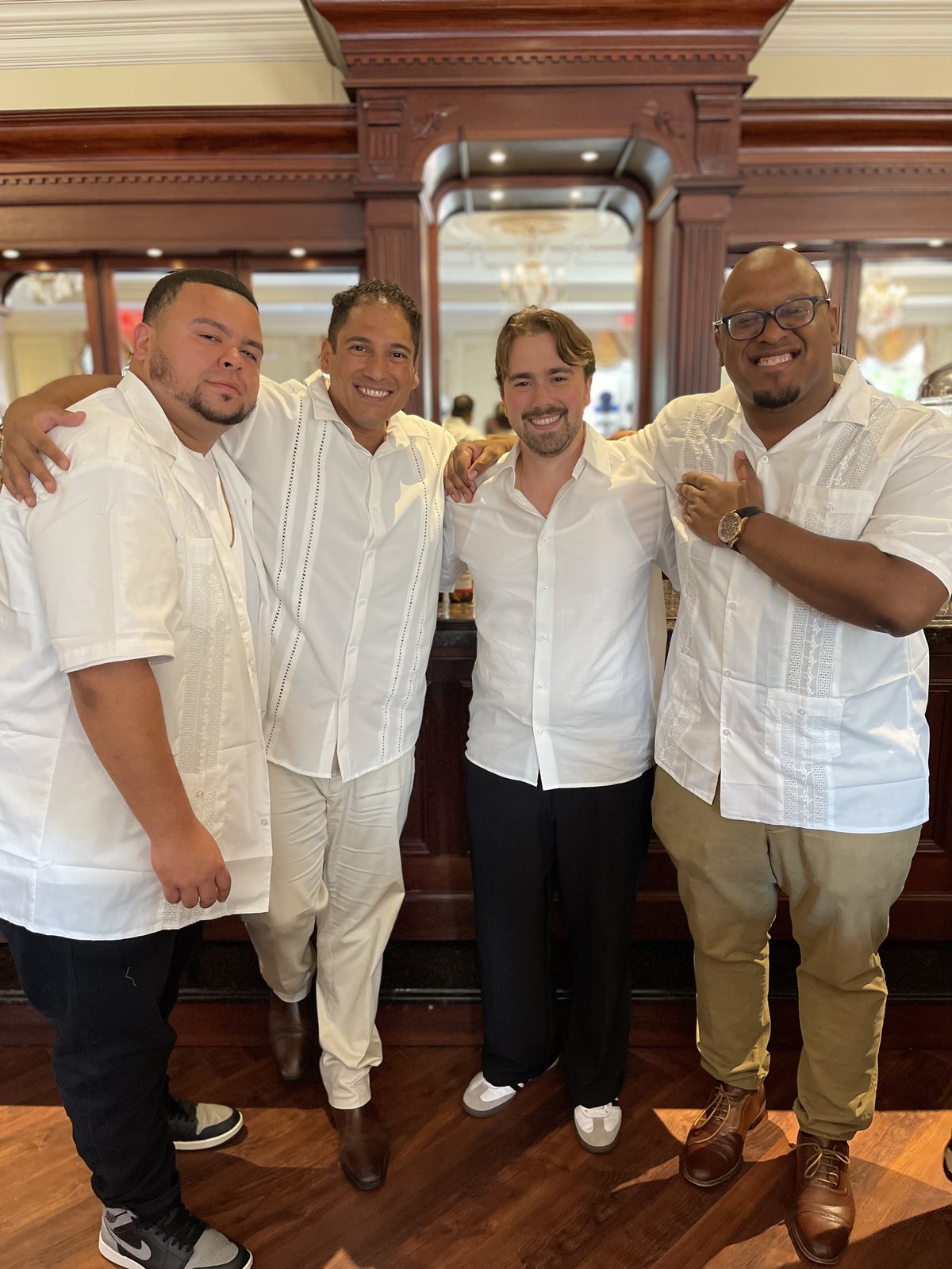 Four friends in white shirts posing together indoors