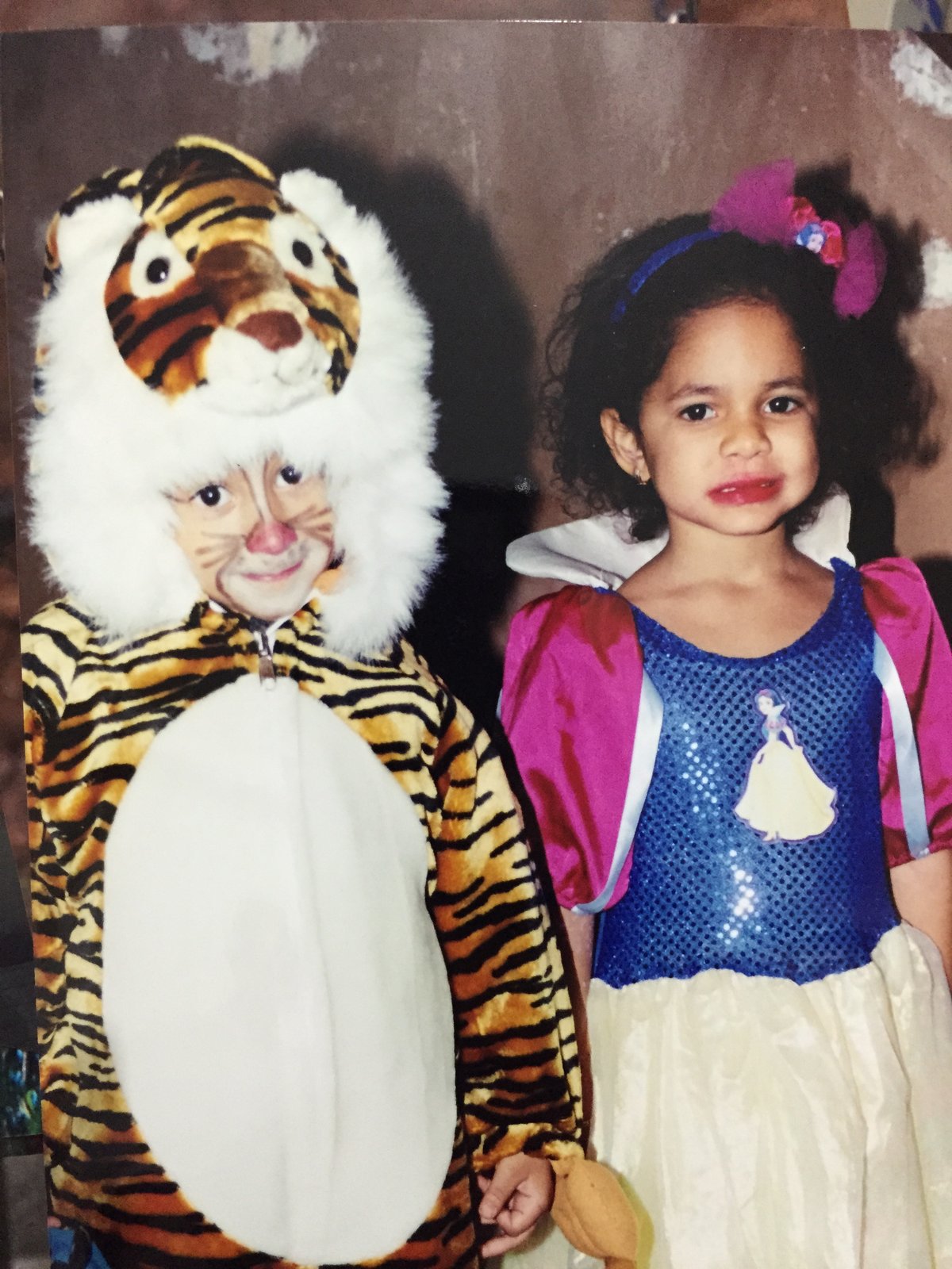 A childhood photo of a girl in a costume beside a tiger suit