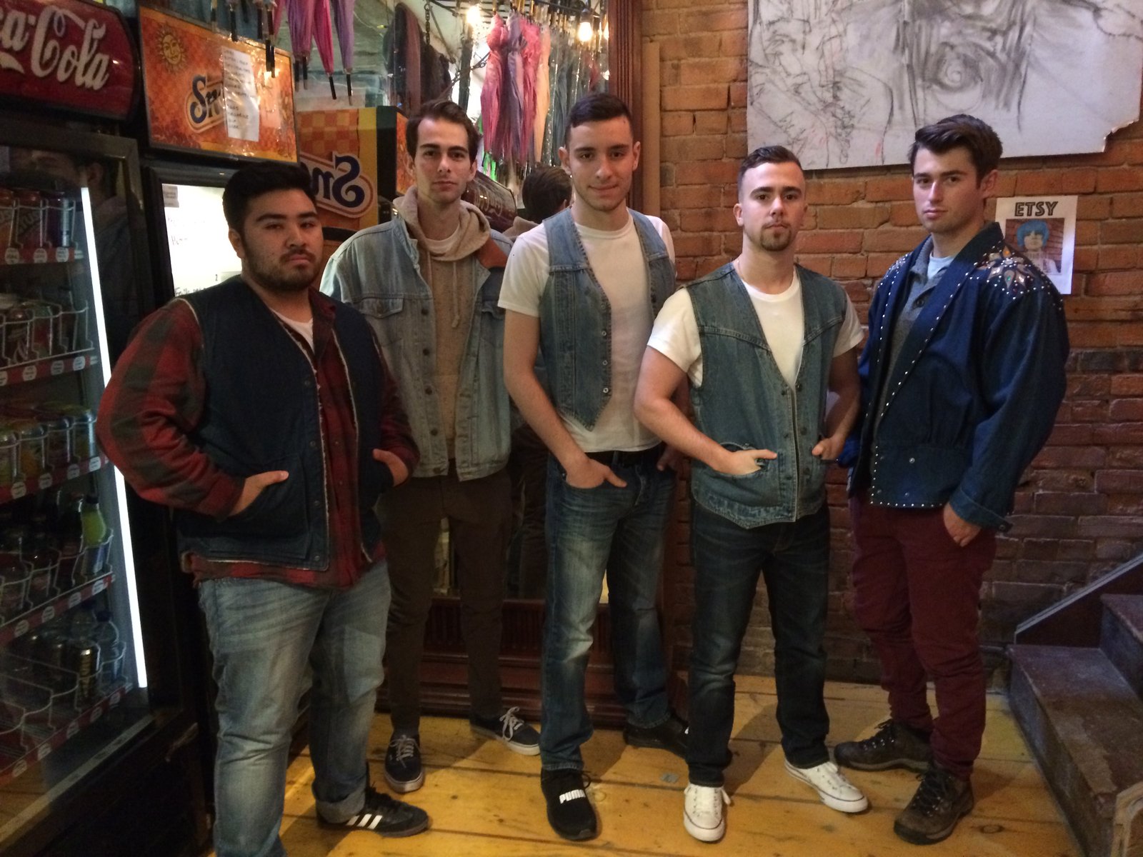 Five friends in denim jackets and vests lined up in a shop