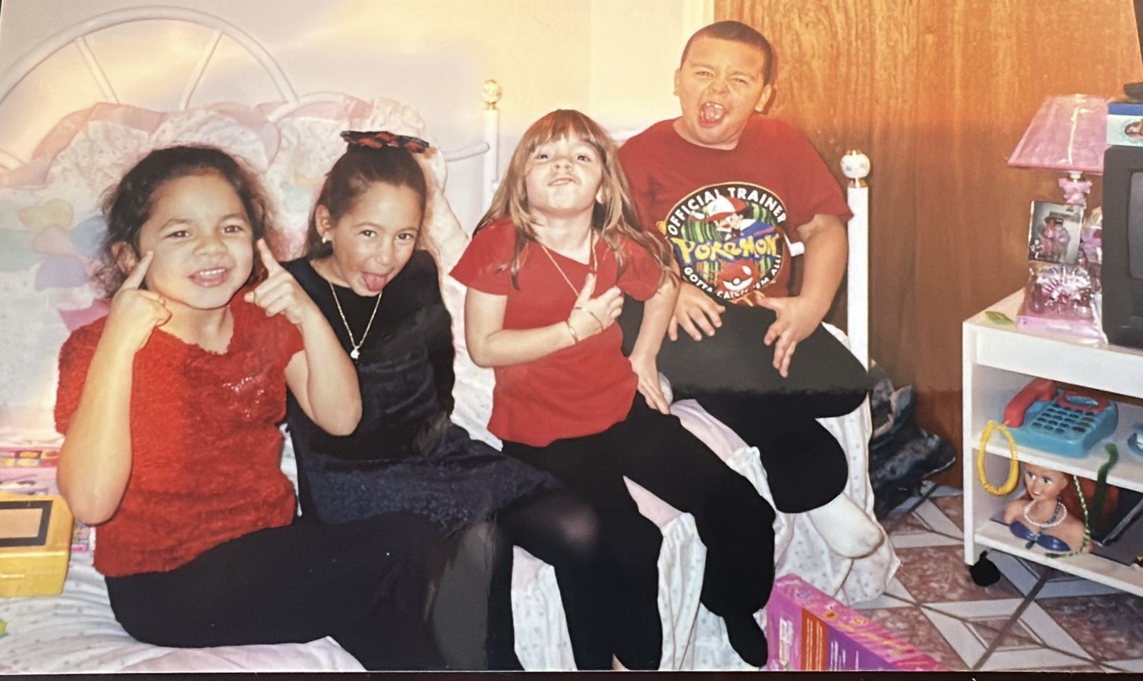 Four children clowning around on a bed at a childhood party