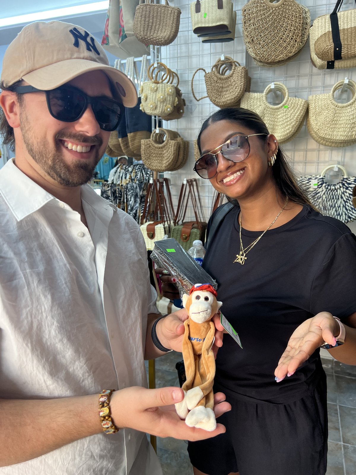 Austin and Bianca at a market holding up a stuffed monkey souvenir