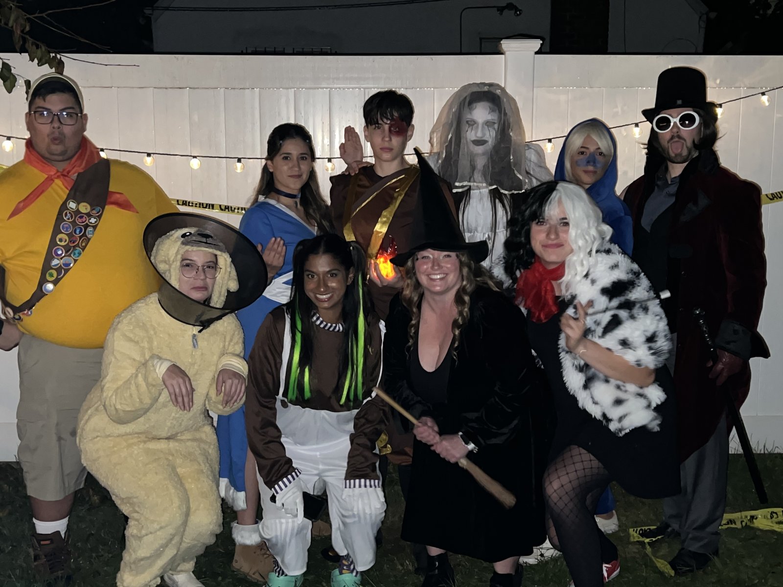A large group of friends in Halloween costumes posing in a back yard