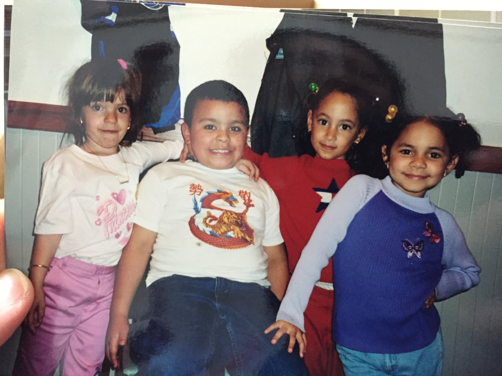 Four young children posing together against a wall