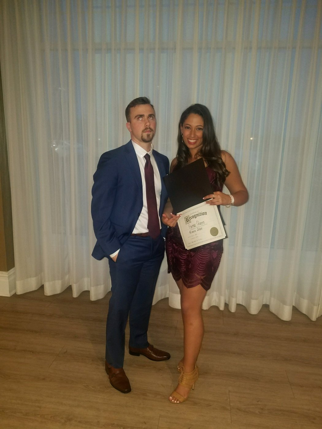 Austin and Bianca dressed up at a formal event, holding a certificate
