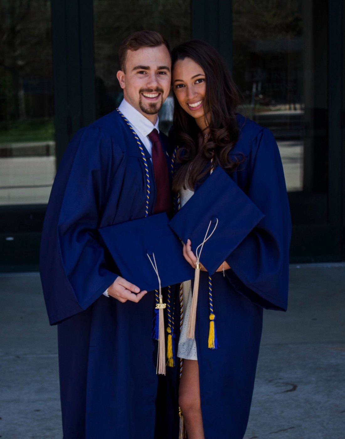 Austin and Bianca in navy graduation gowns and caps