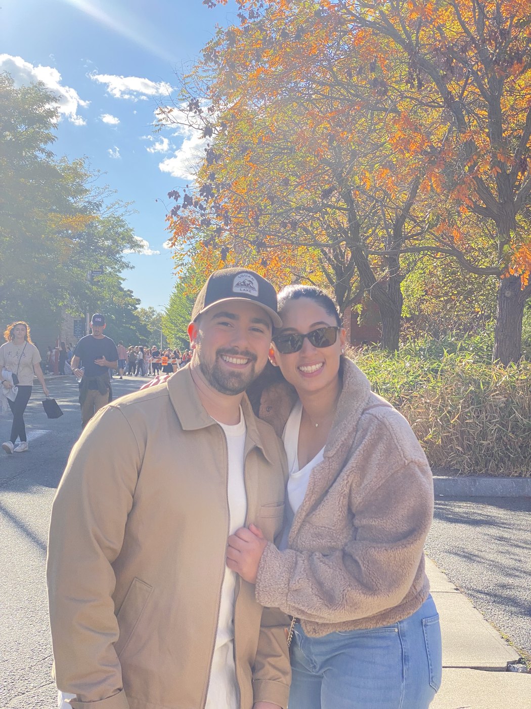 Austin and Bianca outdoors on a street lined with autumn foliage