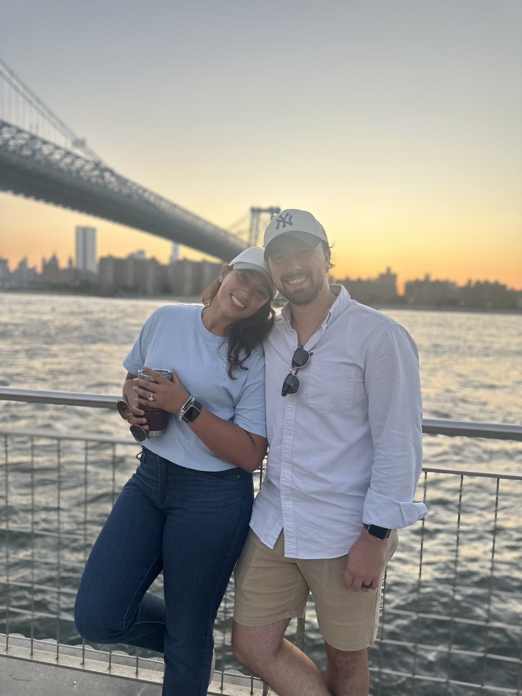 Austin and Bianca by the water at sunset with the Williamsburg Bridge behind them